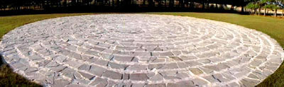 stone labyrinth picture on grassy field with trees in background